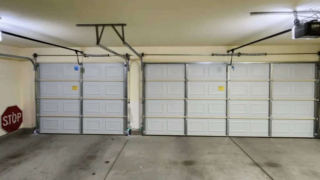 Spacious two-car garage with white doors and a stop sign in the corner. Clean and organized interior view.