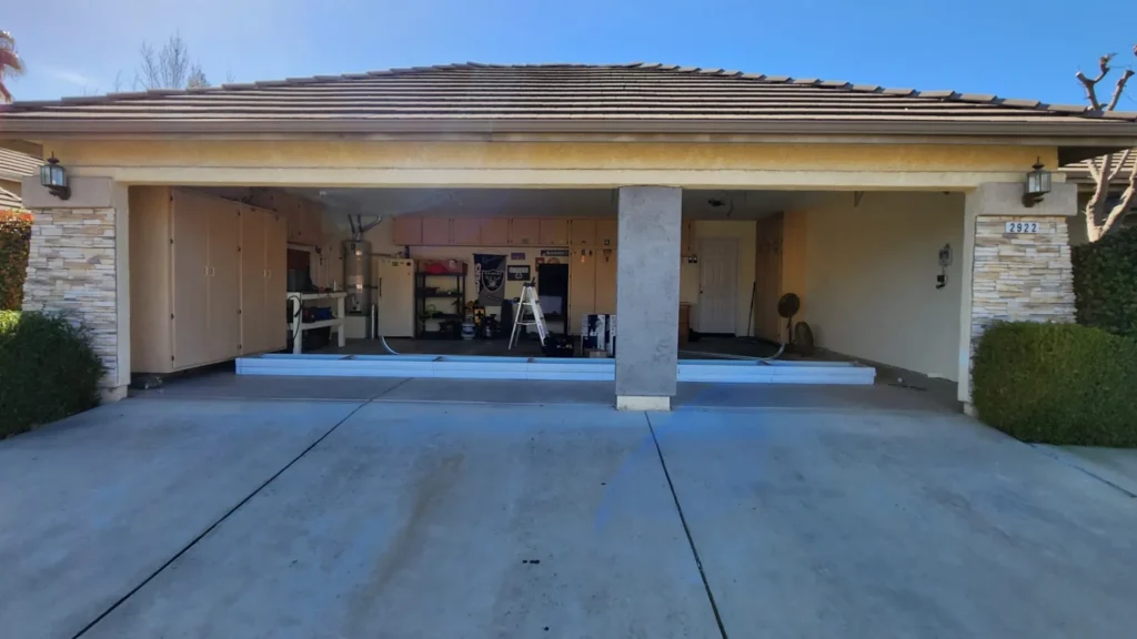 Open two-car garage with storage shelves and workshop tools inside.