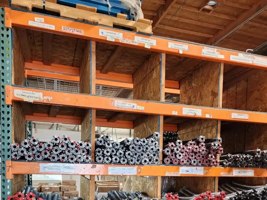 Industrial warehouse shelves filled with stacked metal pipes in an organized arrangement.